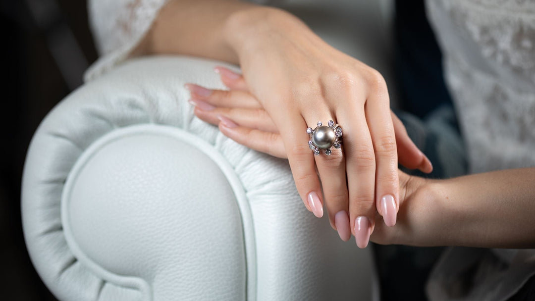 Grey Tahitian pearl ring with diamond halo worn on the hand.